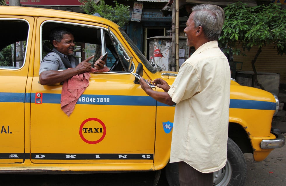 Man pays a taxi driver using mobile phone in India.