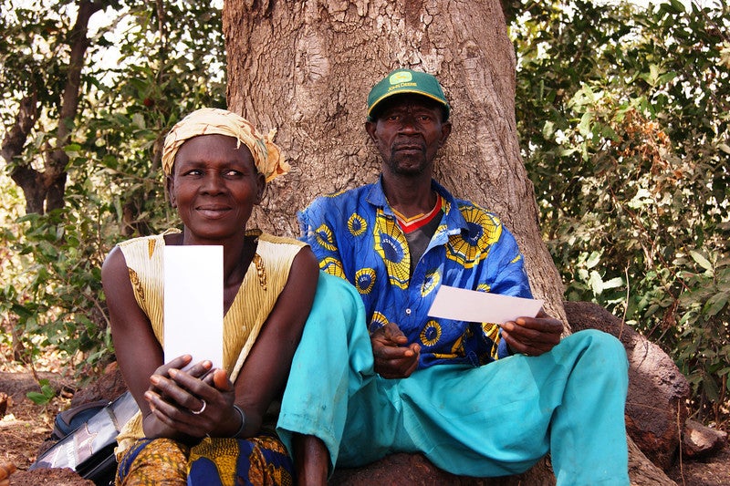 A man and woman sit holding loan checks