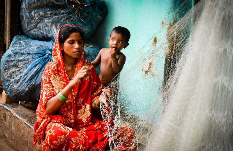Woman in rural India weaving with her baby close to her.