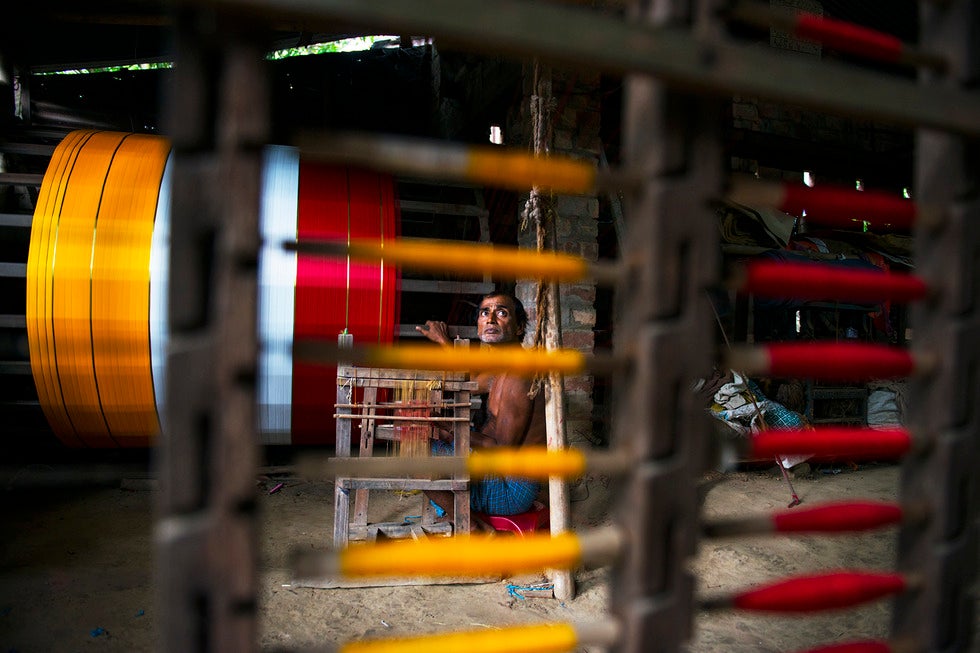 A man sits in a colorful textile factory.