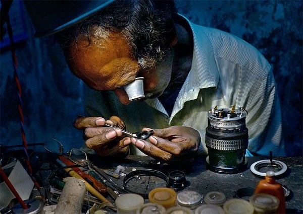 A man uses a magnifier to repair a camera.