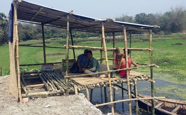 Men in Bangladesh sit in a guardhouse by a fishpond