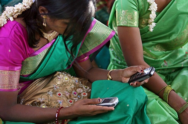 Young women look at their cellphone during a community meeting