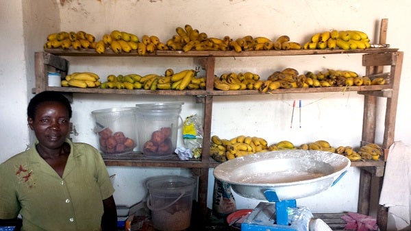 Woman stands next to shelves of bananas, Rwanda