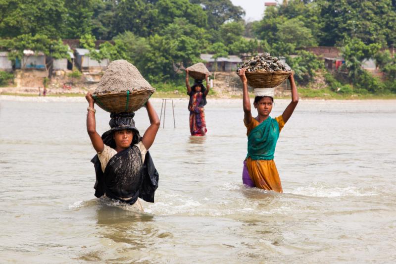 Women carrying wares across the river, India. Photo by Arka Dutta, 2014 CGAP Photo Contest. 
