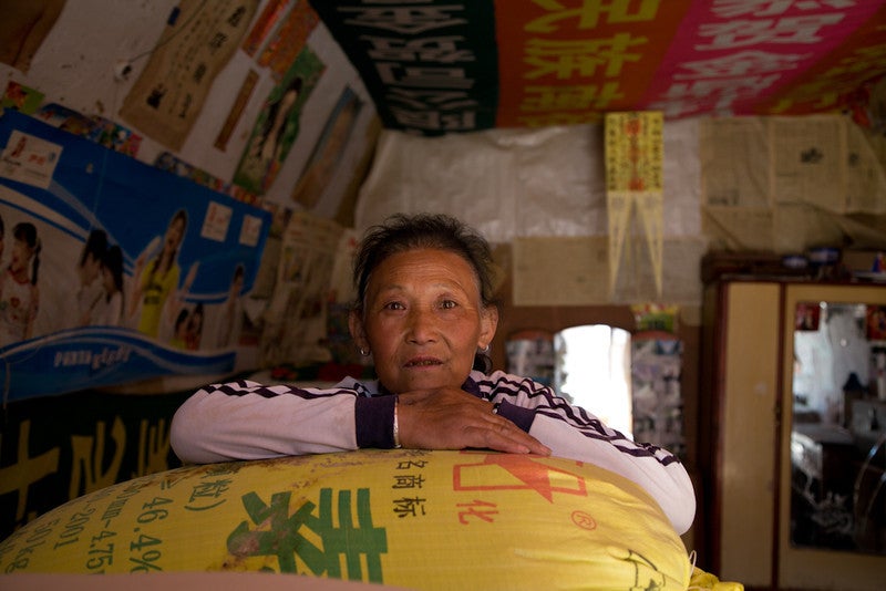 A woman leans on a bag of rice