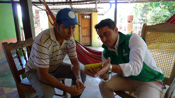 Crezcamos officer and customer look at an informational video on a smartphone in Colombia