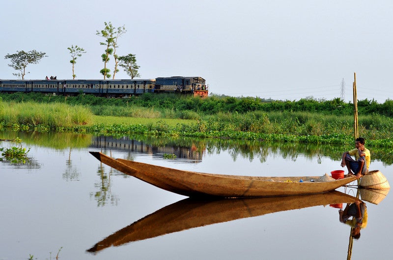A man is fishing in Bangladesh near train tracks
