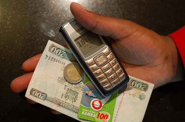 A mobile phone and Kenyan Shillings
