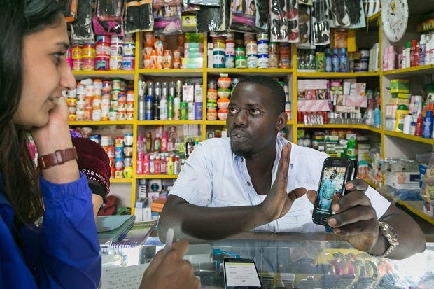 Man demonstrates a mobile phone screen in a ministore