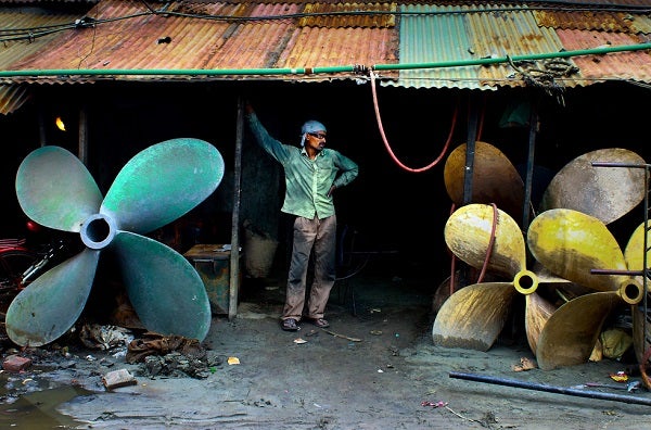 A worker at a shipyard stands between propellers
