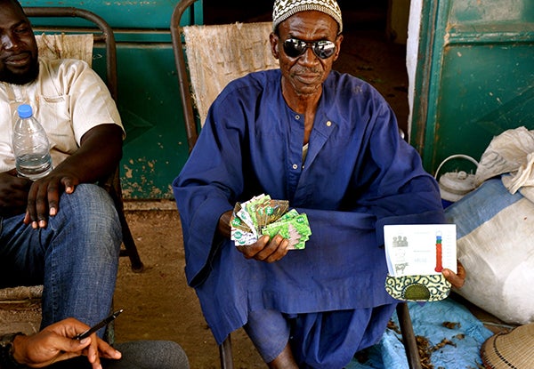 A farmer in Senegal holds up scratch cards