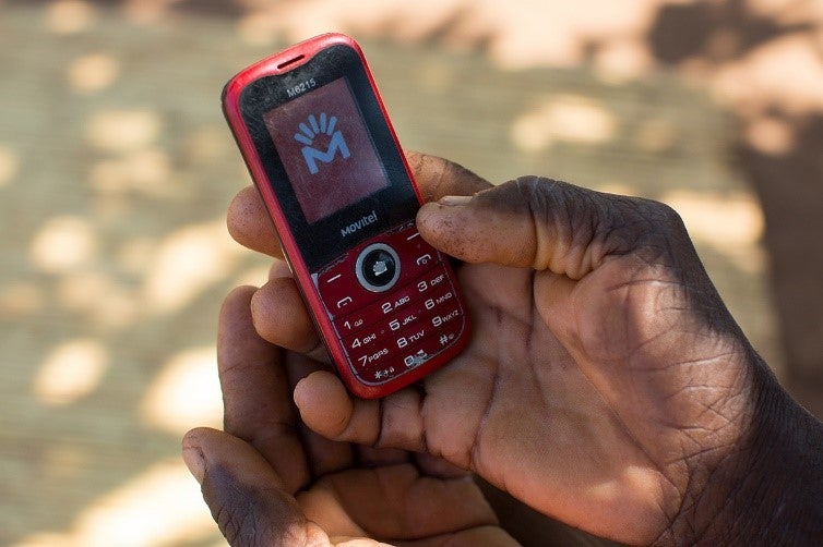 A smallholder holds his phone in Mozambique. Basic phones like these remain popular among low-income customers in emerging markets. Photo: Allison Shelley