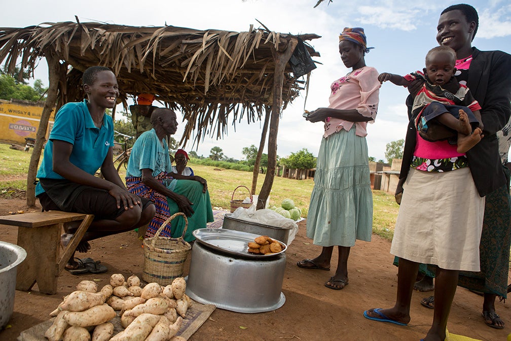 A woman pays cash for eggplants and tomatoes in rural Uganda. Photo: Allison Shelley