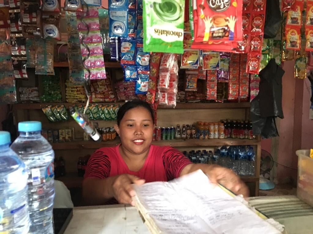 Woman who serves as a cash-in/cash-out agent behind the counter at her store. Photo: Vered Konijnendijk, CGAP