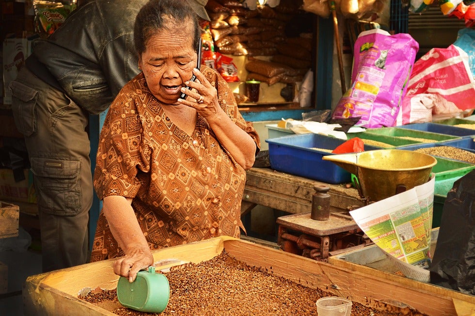 A merchant uses her mobile phone in Indonesia.