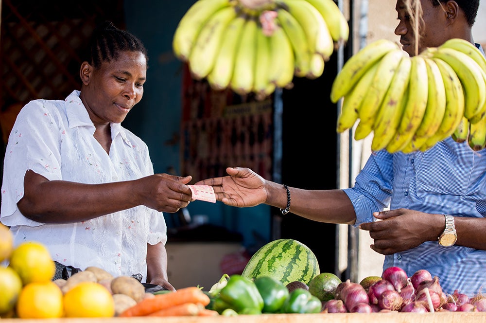 A produce merchant in Tanzania accepts a cash payment. Photo: Peter Boniface, 2016 CGAP Photo Contest