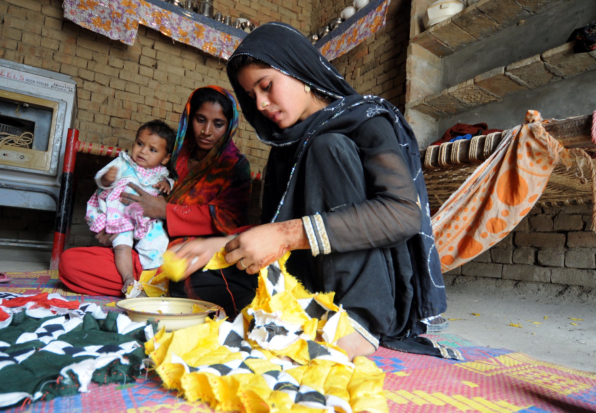 A woman stitches a bed cover at her home in Taunsa, Pakistan.
