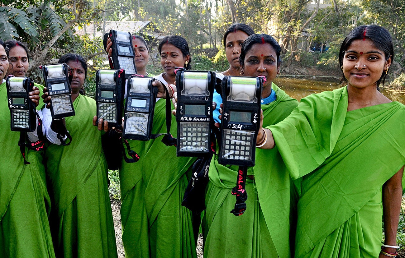 Women agents of a microfinance institution in India show the devices they use for collections.