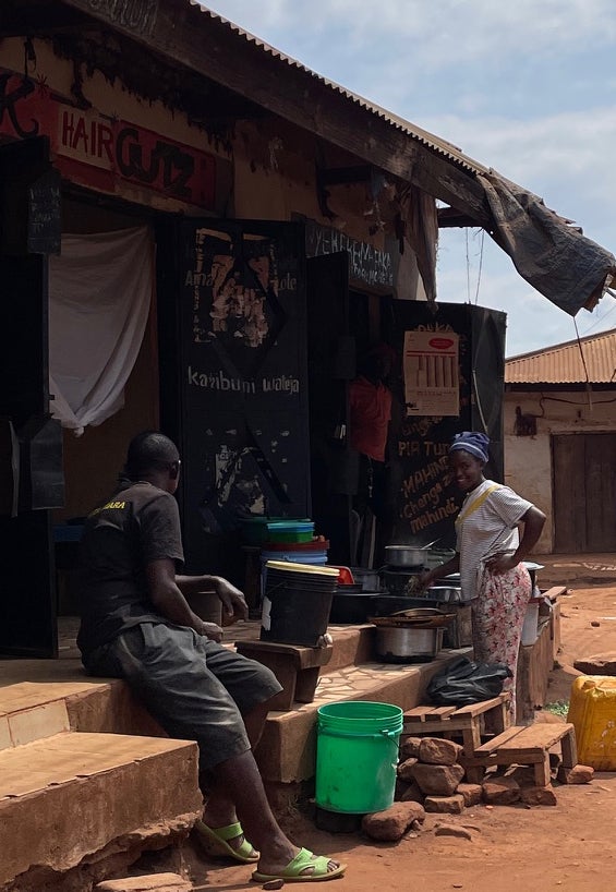 A woman stands near a doorway off a street