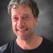 headshot of man in dark shirt against gray background