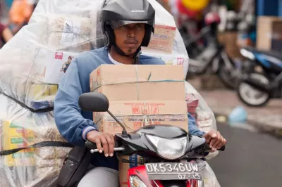 a delivery man on his bike with boxes of items behind him and on his lap