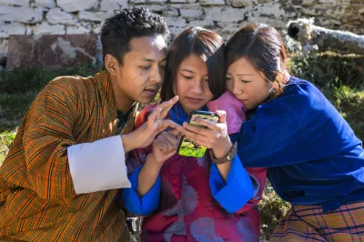 Three people look at a smartphone screen. Photo: Bhutan Anindya Majumdar, 2017 CGAP Photo Contest