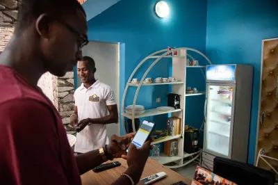 A man can be seen checking a payment application developed by the company at Le Crypto, a crêpe restaurant in the Para Djicoroni district of Bamako, Mali, where it is possible to pay in Kingui, a cryptocurrency developed by the FAMIB Group.