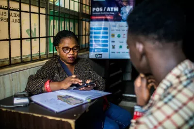 Using her mobile phone, OLUBAM Enterprises’ digital finance agent Ajayi Yemisi completes a mobile money transaction for a customer