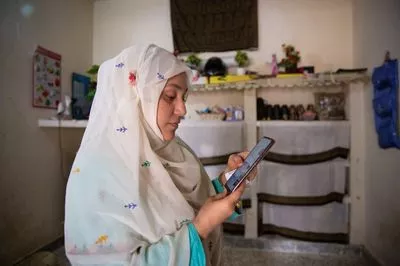 Women using smartphone to check her finances in a rural area Pakistan 