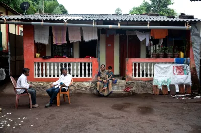 A rural CICO agent sits outside a family home