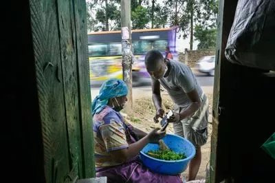 A vegetable seller from Kenya and her customer using a mobile money app on their phones