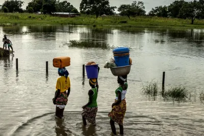 female farmers walking through water with baskets on their heads