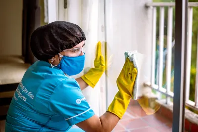 a woman in a mask and gloves cleaning a window in a home