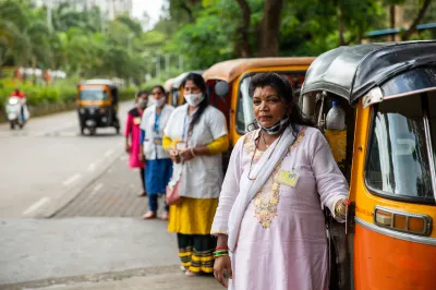 Woman rickshaw drivers in India stand outside their vehicles