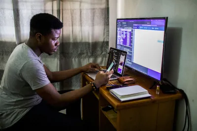 A young man looks at his phone and computer screen