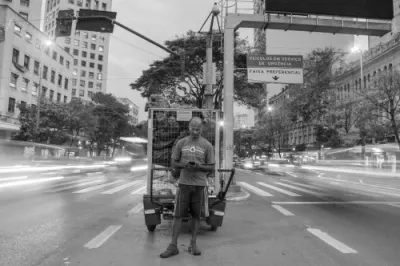 black and white photo of a man standing in the middle of a busy street on his phone