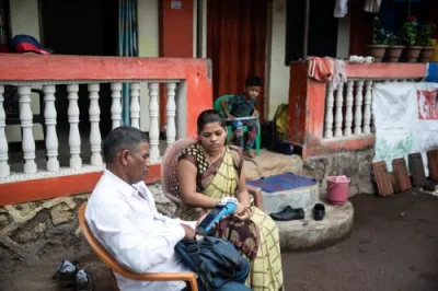 a male collects a deposit from a female client as they sit in front of a home in india