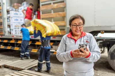 woman looks at her mobile phone in front of a truck being unloaded