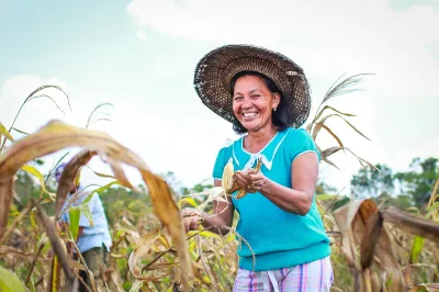 A woman smiles as she works in a field in the Philippines