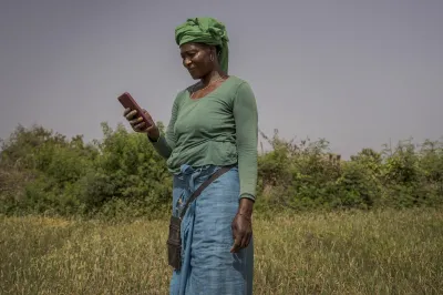 A woman in a field looks at her mobile phone