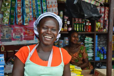 an African female woman smiles at the camera in a small grocery shop