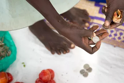 A merchant in rural Uganda transacts in cash