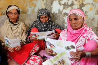 A group of women reads about a savings program in Pakistan.