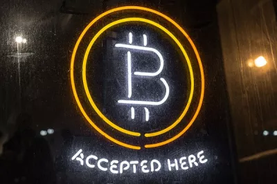 The Bitcoin logo glows in lights in a window