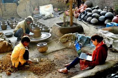 A girl studies on her computer while her family works on pottery