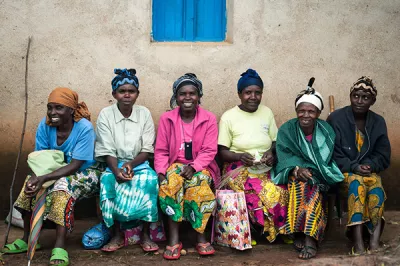 In Rwanda, women wait to receive planting supplies including hybrid seed and fertilizer they purchased on credit from a social enterprise called One Acre Fund .