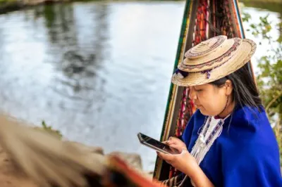 Columbian woman in a tan hat looking at her mobile phone 