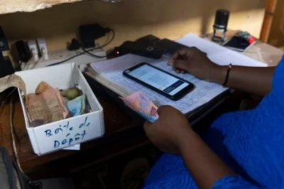 a woman counting cash and filling out ledger at her desk in Cote D'Ivoire