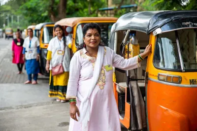 a group of women standing in front of their rickshaws